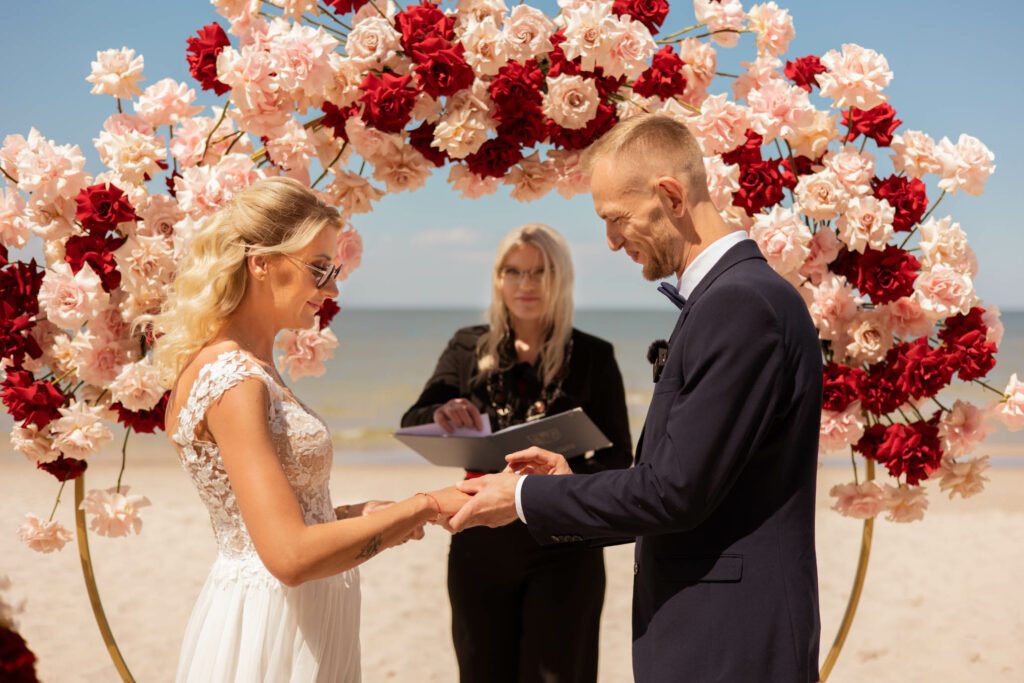 Para młoda zakłada sobie obrączki podczas ceremonii ślubnej na plaży
