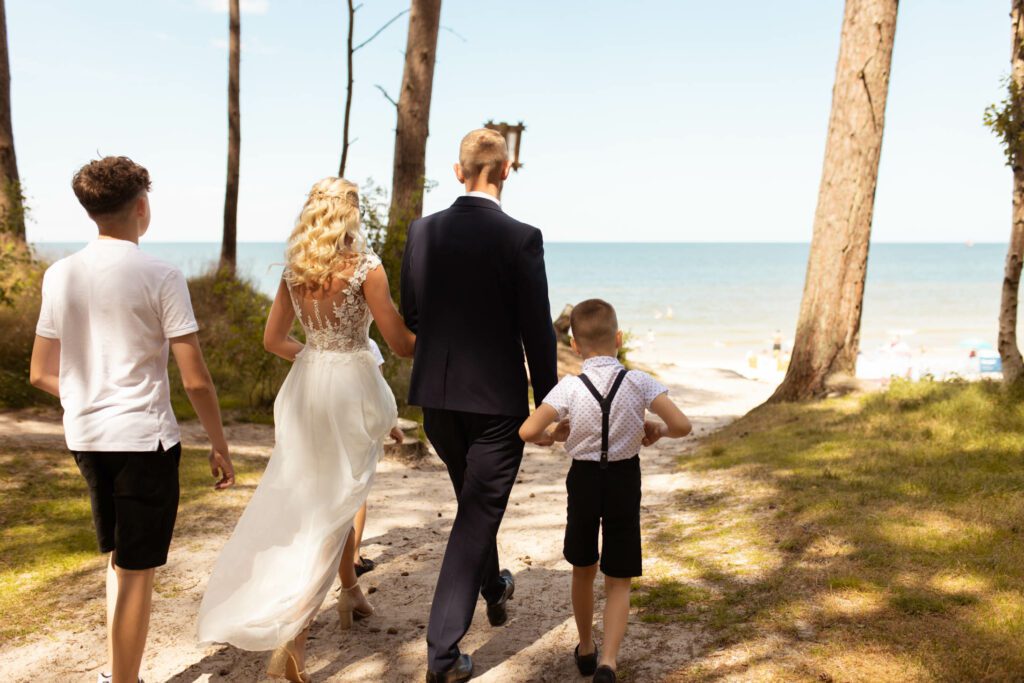 Para Młoda z dziećmi idąca na ślub na plaży