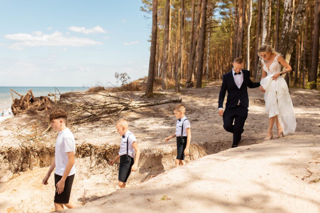 Para młoda z dziećmi idąca na ślub na plaży